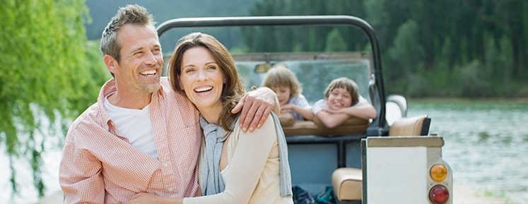 family smiling in front of a lake