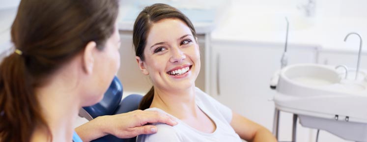 brunette woman smiling after her root canal procedure as her dentist pats her shoulder
