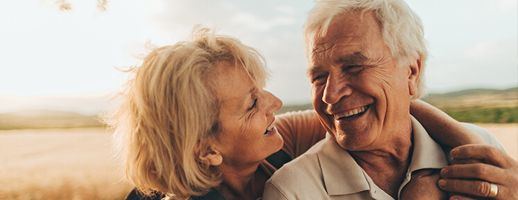 An older couple with dentures smiling at each other