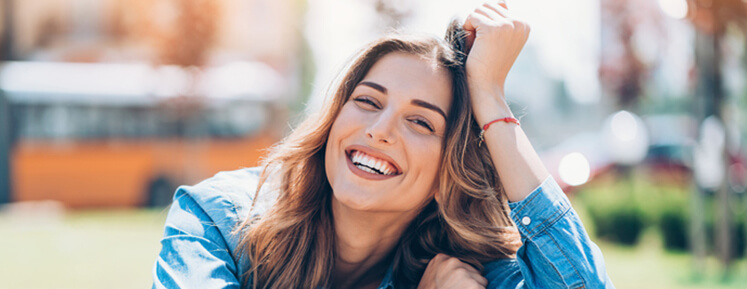 woman smiling wearing a jean jacket showing her pretty white teeth