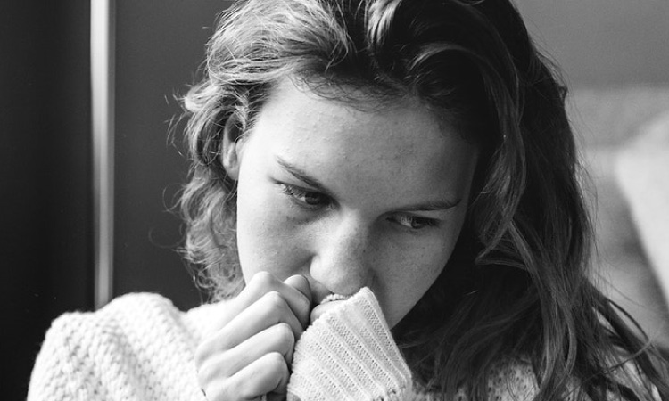 girl looking down covering her mouth experiencing anxiety