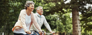An older couple in sweaters riding bikes