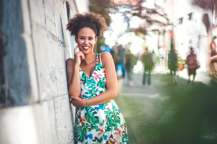 Brunette woman wearing a floral summer dress smiles with dental implants