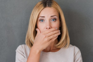 woman covering her mouth with her hand to hide receding gums
