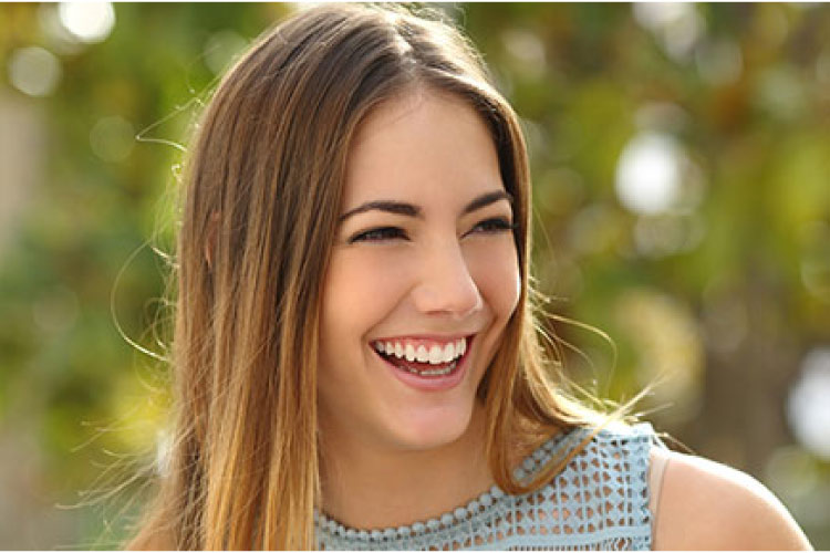 young woman smiles to show off her Invisalign corrected smile