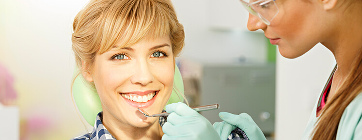 smiling woman having her teeth examined by a dentist