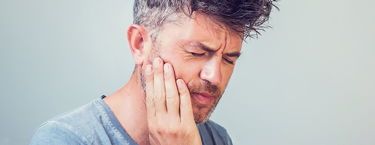 man holding his jaw in pain