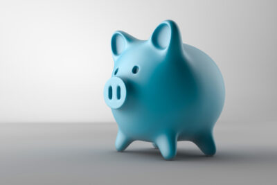 Blue piggy bank on a gray background to symbolize saving money with our in-house dental plan