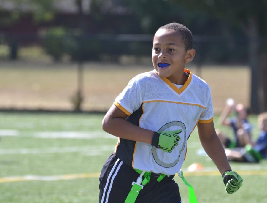 Young male athlete smiles with a sports mouthguard while playing flag football