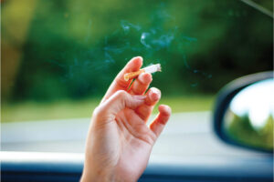 hand holding a burning cigarette out a car window